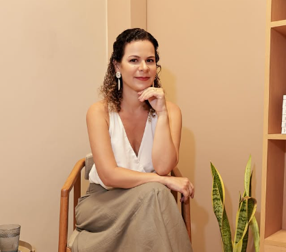 Julianna Queiroz, psicanalista, sentada em seu consultório em ambiente acolhedor